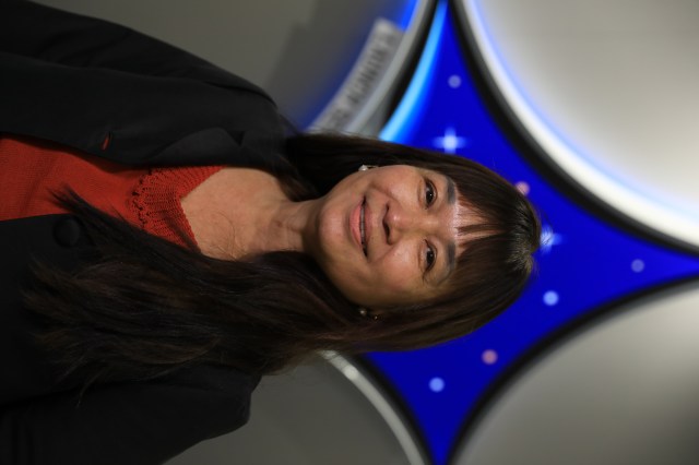 A portrait of Kennedy Space Center's Denise Pham with the Launch Services Program insignia in the background.