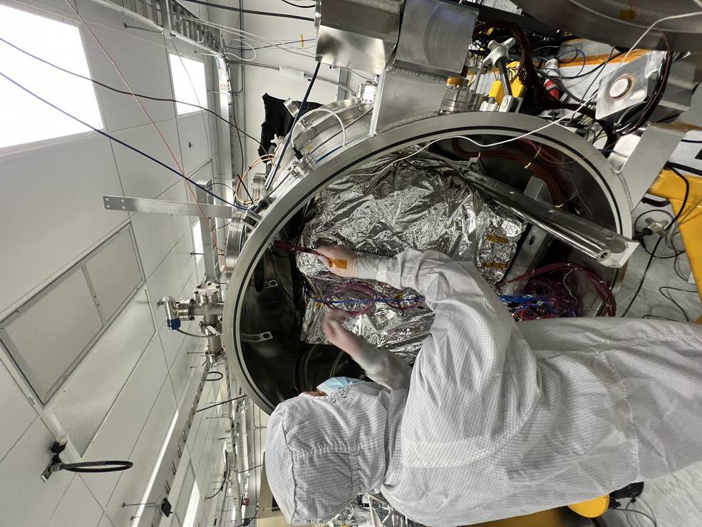 An engineer prepares the imaging spectrometer instrument for testing in a thermal vacuum chamber at JPL.