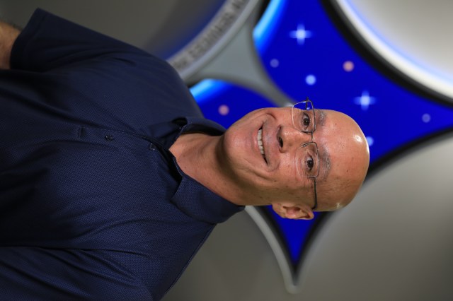 A portrait of Kennedy Space Center's Hamilton Fernandez with the Launch Services Program insignia in the background.