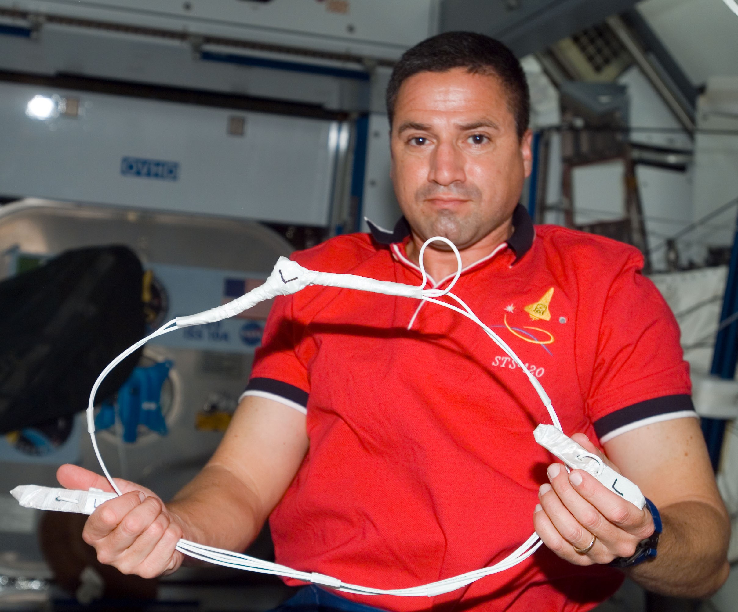 NASA astronaut George D. Zamka holding the cufflink device used to repair the torn solar array