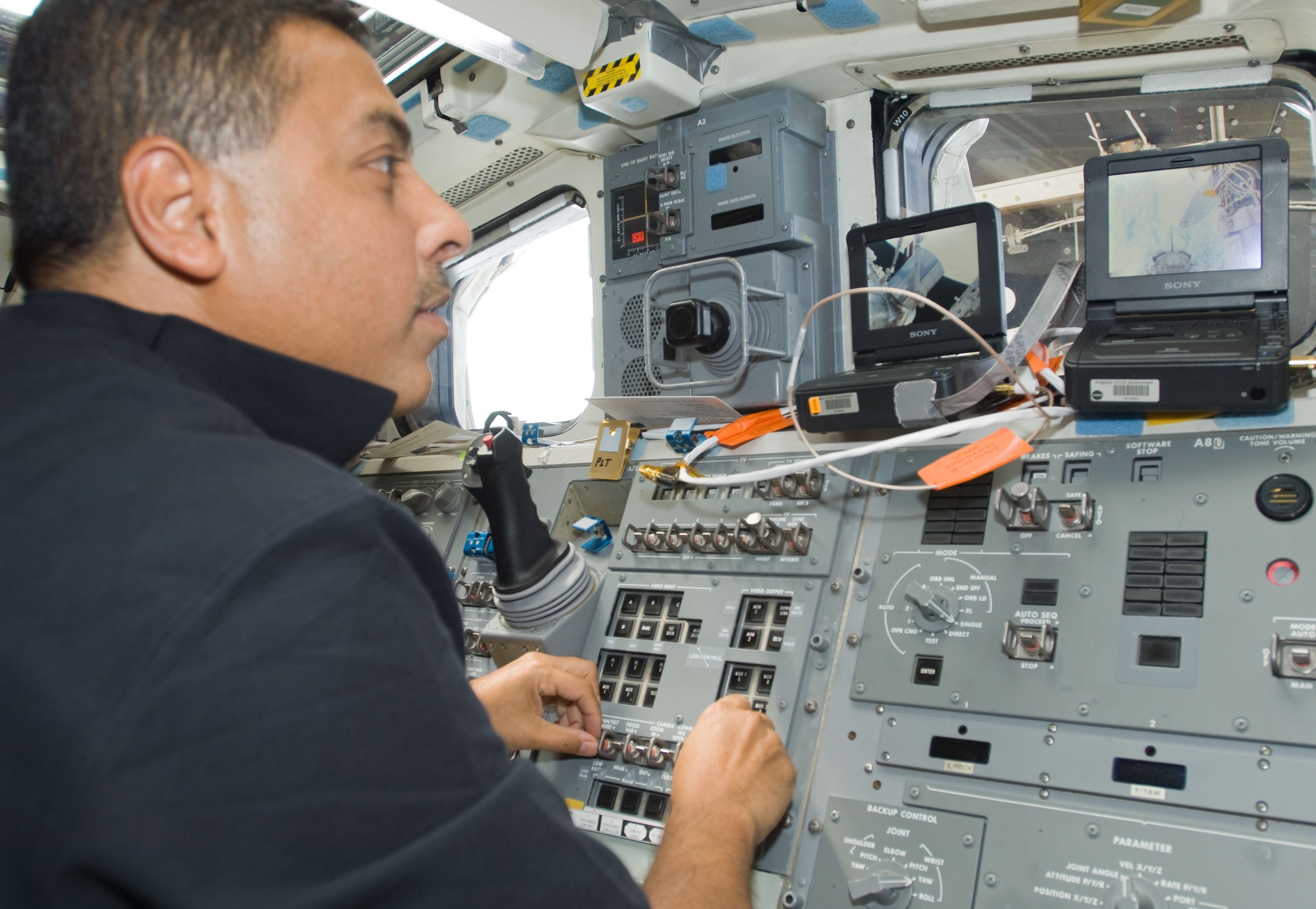 NASA astronaut José M. Hernández operating the shuttle’s robotic arm to transfer the Leonardo Multipurpose Logistics Module (MPLM) to the station.