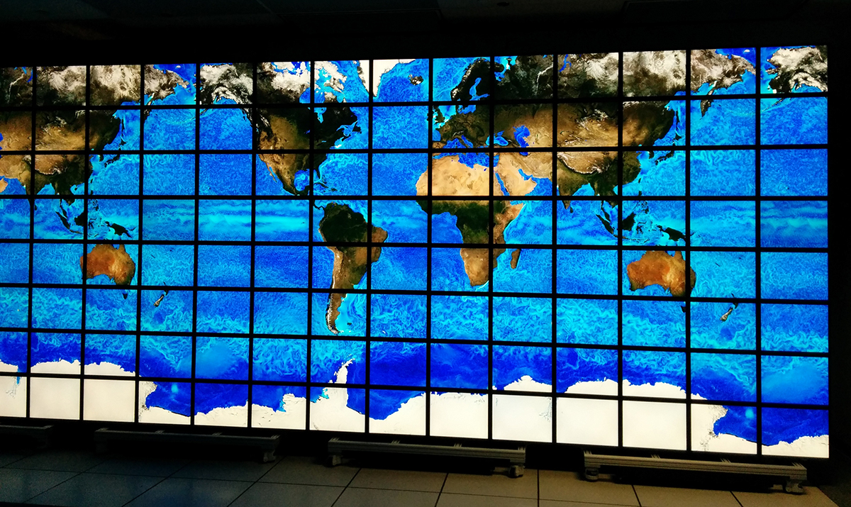 a wall of many displays together, displaying a map of the world showing ocean currents