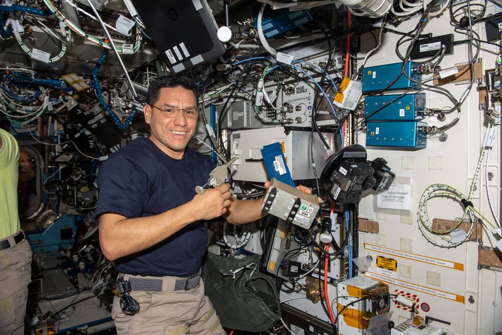 NASA astronaut Frank Rubio uses a tool in his right hand as he activates a space biology experiment that is studying how weightlessness affects genetic expression in microbes.