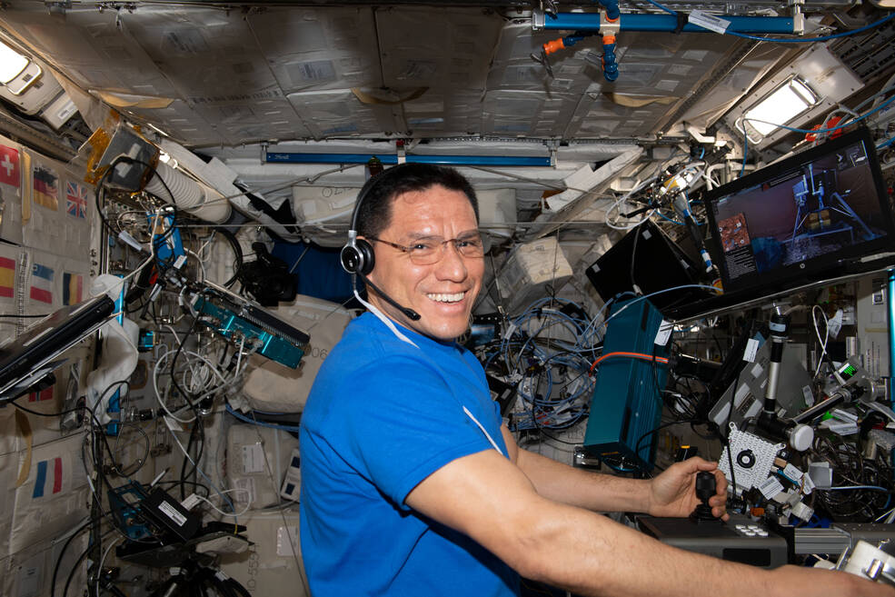 Frank Rubio wears a headset and his hands are on controls as he conducts a session for Surface Avatar, which evaluates the use of haptic feedback when commanding robots remotely.