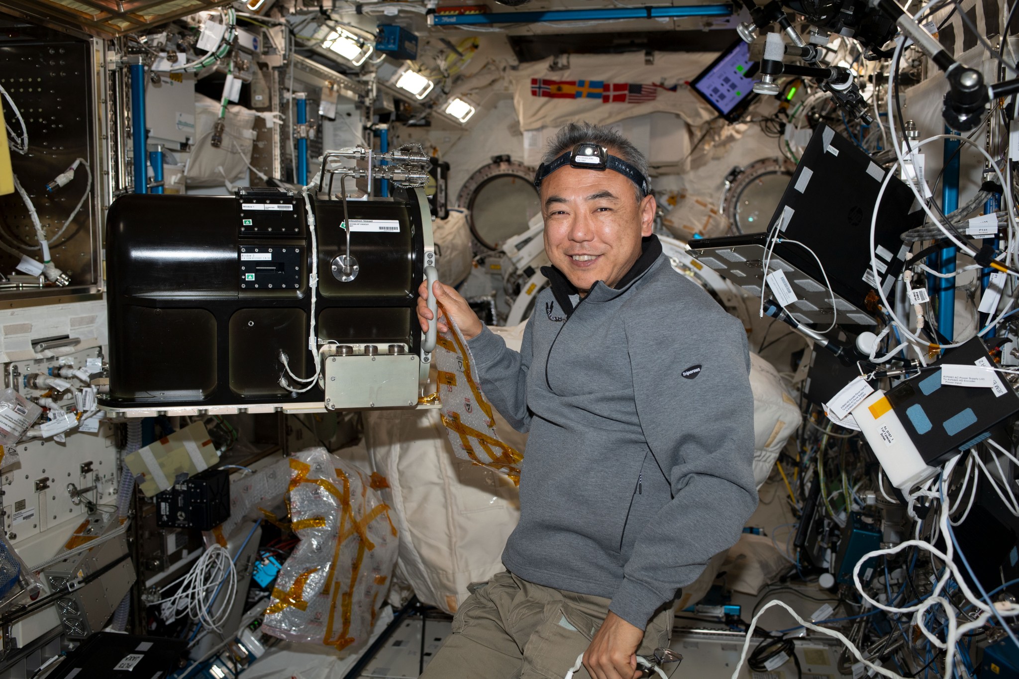 male astronaut setting up hardware for a combustion experiment