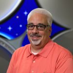 A portrait of Kennedy Space Center's Jorge Piquero with the Launch Services Program insignia in the background.