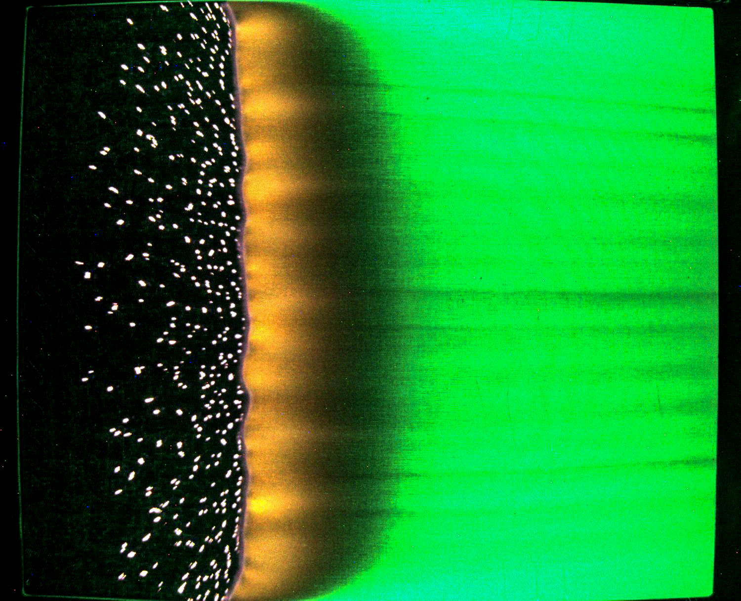 green fabric burns from left to right with particles of ash on the left and a flame line in the center