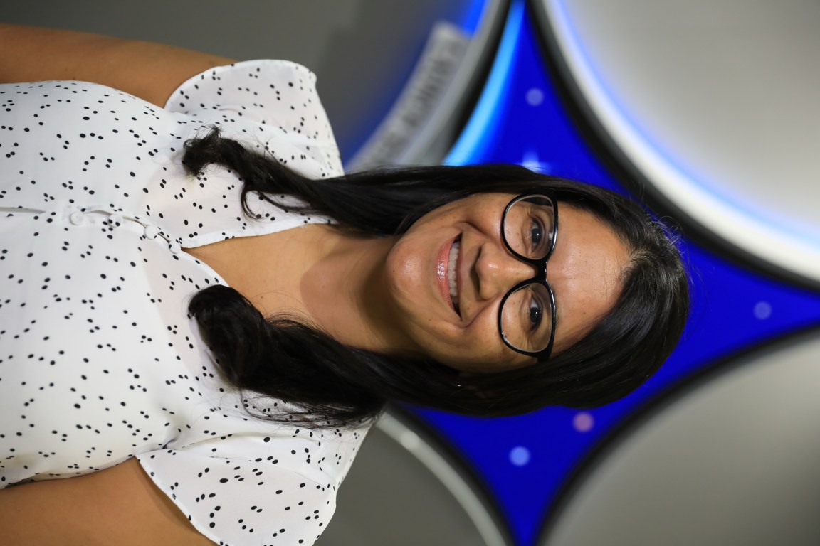 A portrait of Kennedy Space Center's Leticia Gomez with the Launch Services Program insignia in the background.