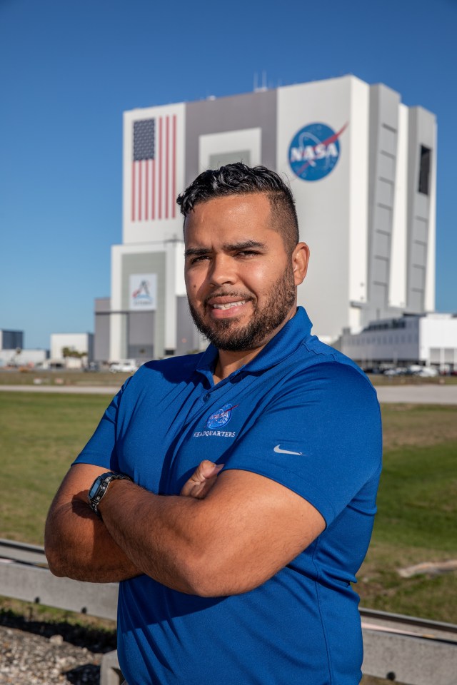 A portrait of Kennedy Space Center's Marcos Peña with the Vehicle Assembly Building in the background.