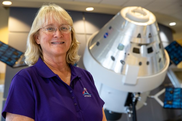 A photograph of Kennedy Space Center's Marie Reed with a mock-up Orion capsule in the background.