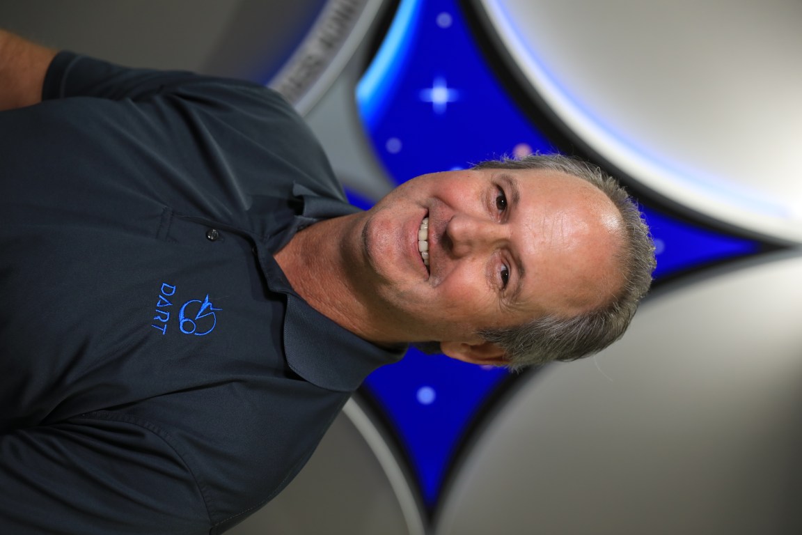 A portrait of Kennedy Space Center's Ralph Mikulas with the Launch Services Insignia in the background.