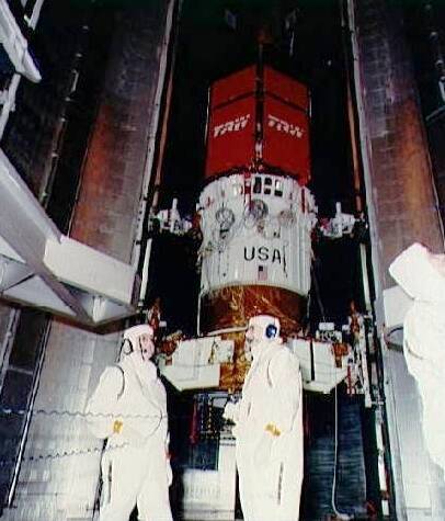 Technicians load the TDRS-3 communications satellite and its Inertial Upper Stage into Discovery’s payload bay