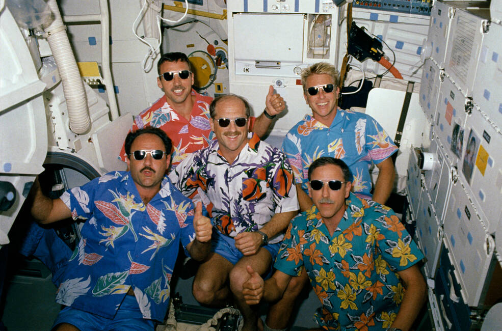 Dressed more casually, the STS-26 astronauts wear Hawaiian shirts presented to them by workers in the Orbiter Processing Facility at NASA’s Kennedy Space Center in Florida