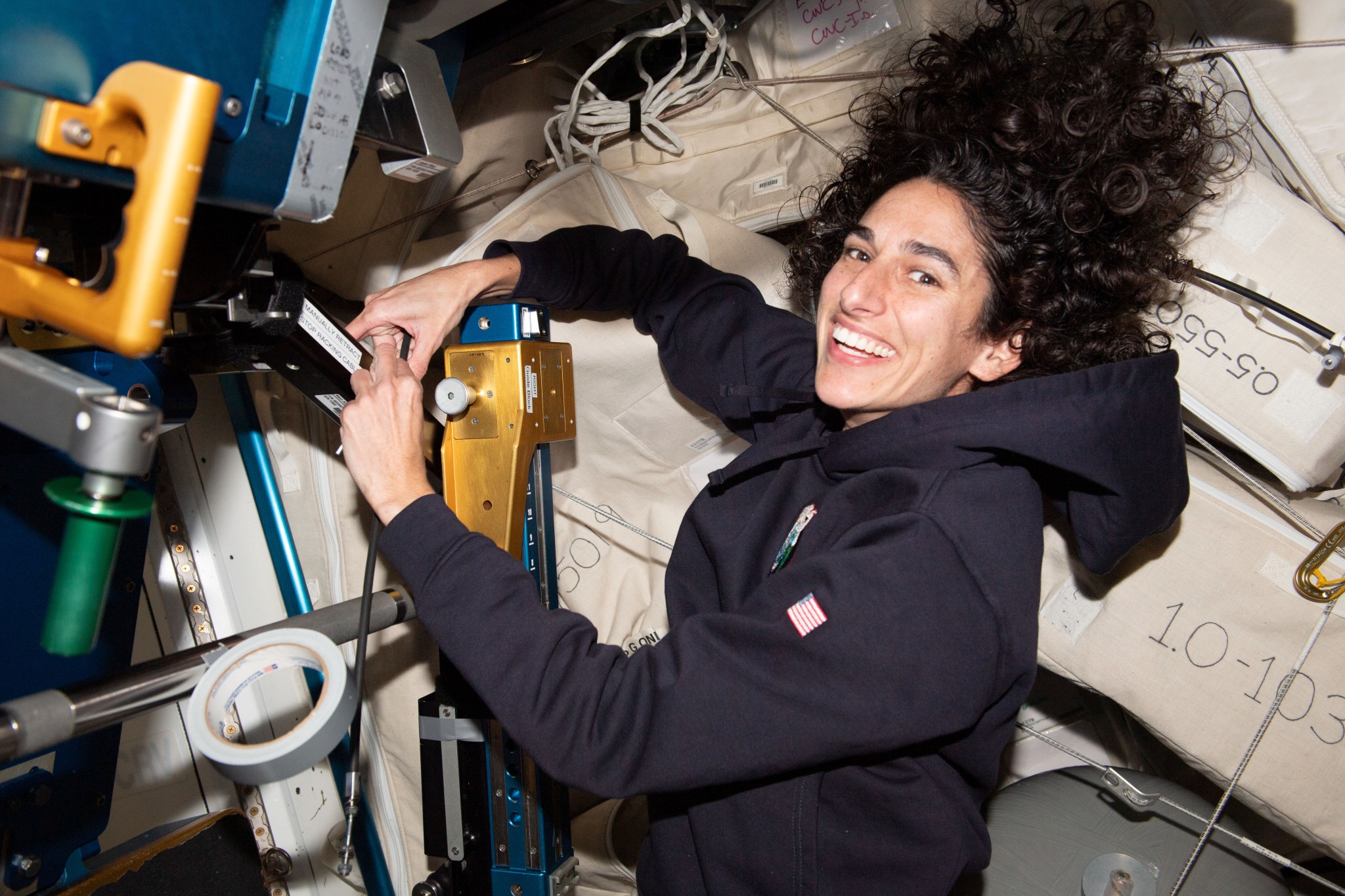 iss070e001602 (Oct. 2, 2023) -- NASA astronaut and Expedition 70 Flight Engineer Jasmin Moghbeli works with the Advanced Resistive Exercise Device, or ARED, removing and replacing cables. The device uses adjustable resistive mechanisms to provide crew members a weight load while exercising to maintain muscle strength and mass in microgravity.