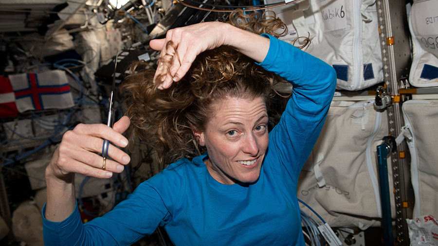 Astronaut Loral O'Hara is pictured trimming her hair aboard the International Space Station.