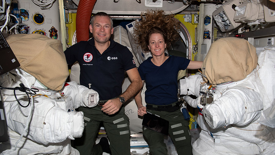 Astronauts Andreas Mogensen and Loral O'Hara work on a pair of spacesuits inside the International Space Station's Quest airlock.