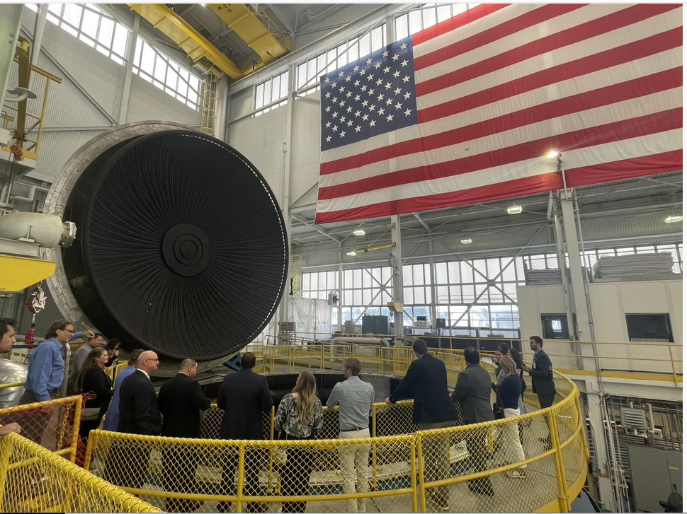 Several visitors gather in a circle to look down into a huge vacuum chamber at NASA’s Neil Armstrong Test Facility.