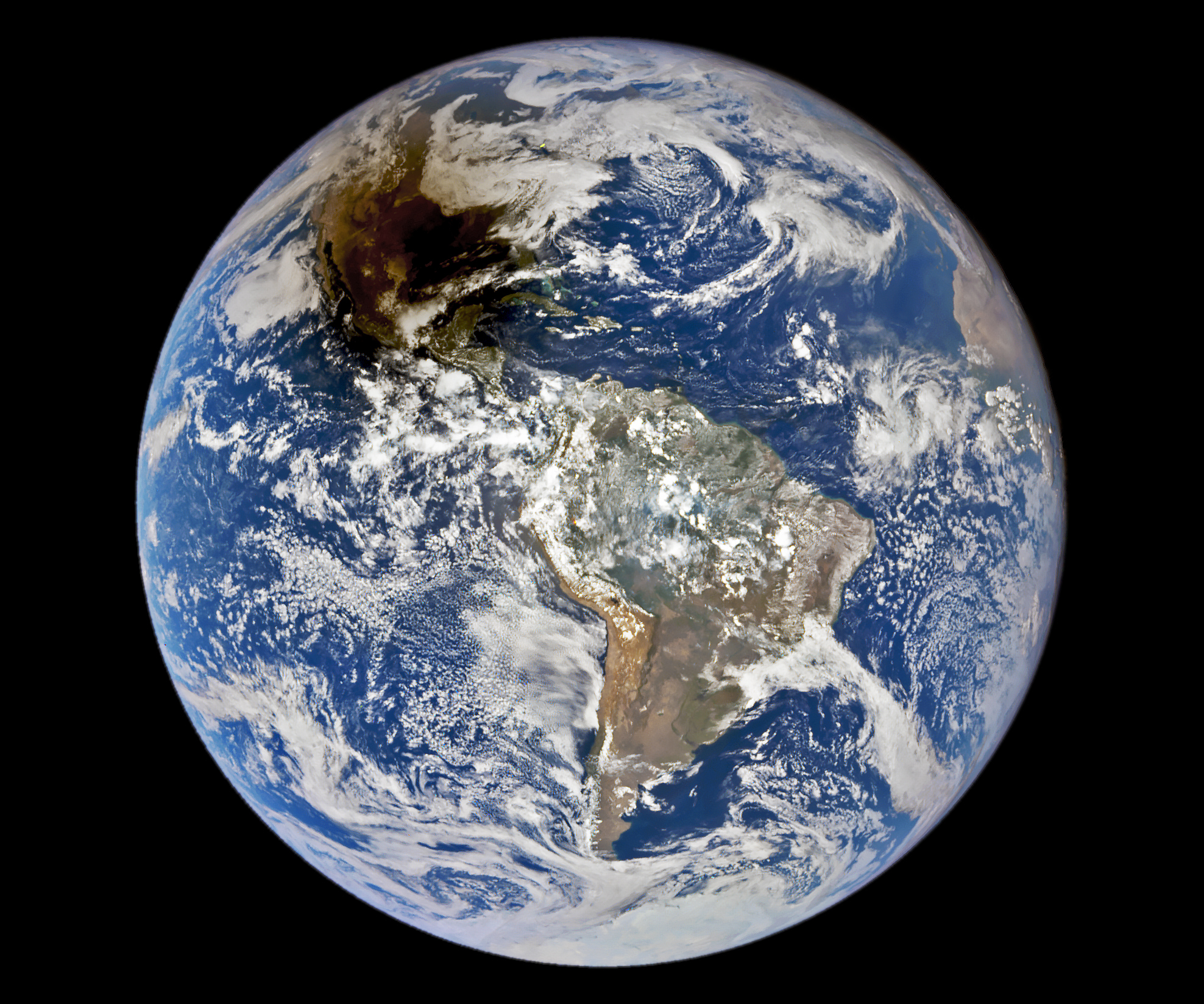 A full disc image of Earth in which North and South America are visible. The Moon casts a dark brown shadow in the top left quadrant.