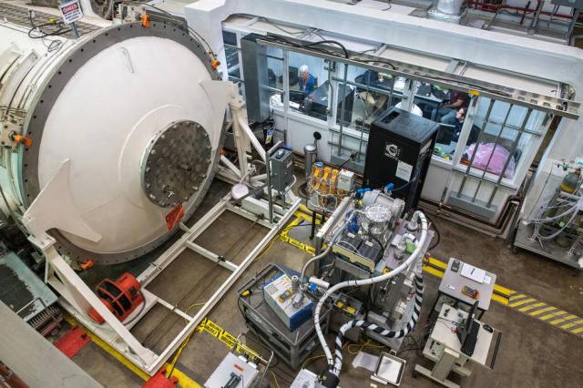 view from above of the equipment in the electric propulsion test facility with researchers inside a glass wall.