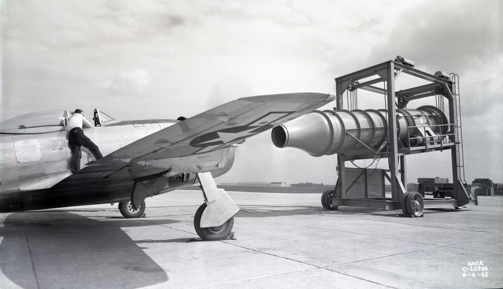 Aircraft on tarmac in front of blower equipment.