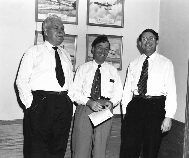 Three men standing in office.