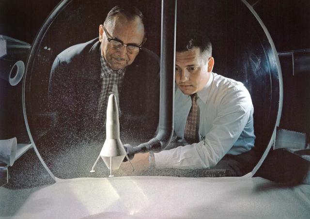 Two men looking at dust inside glass.