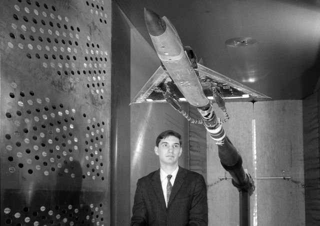 Man looking at model in wind tunnel.