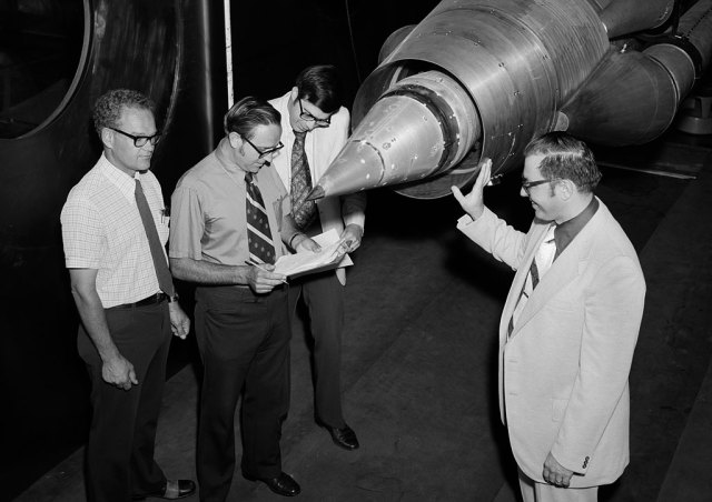Three men examining engine in test section.