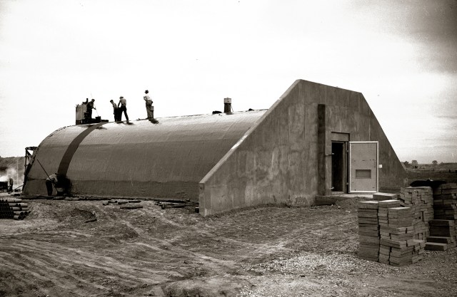 Workers on curved roof of concrete bunker.