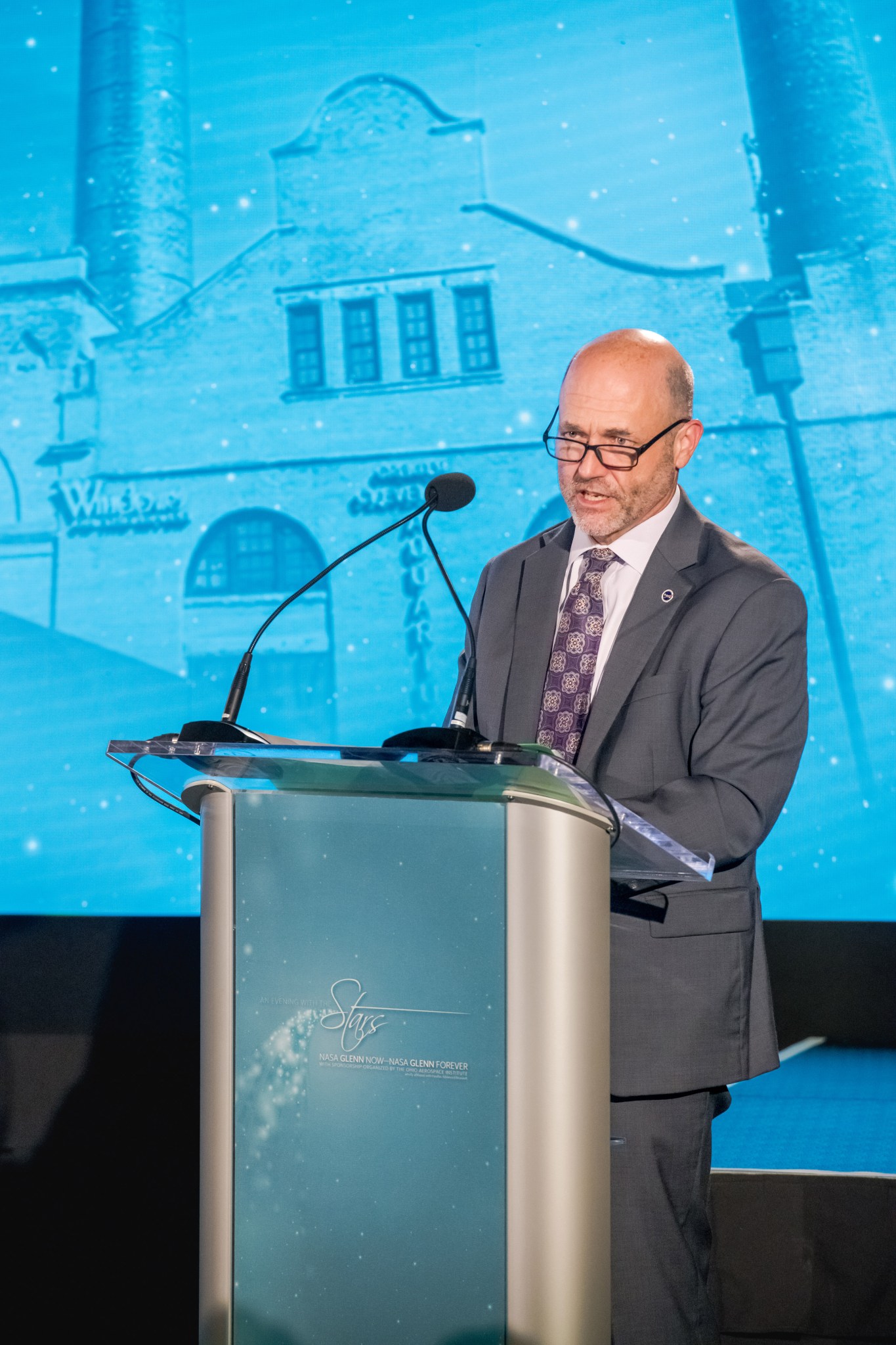 Center Director Dr. Jimmy Kenyon addresses an audience from a podium on stage.