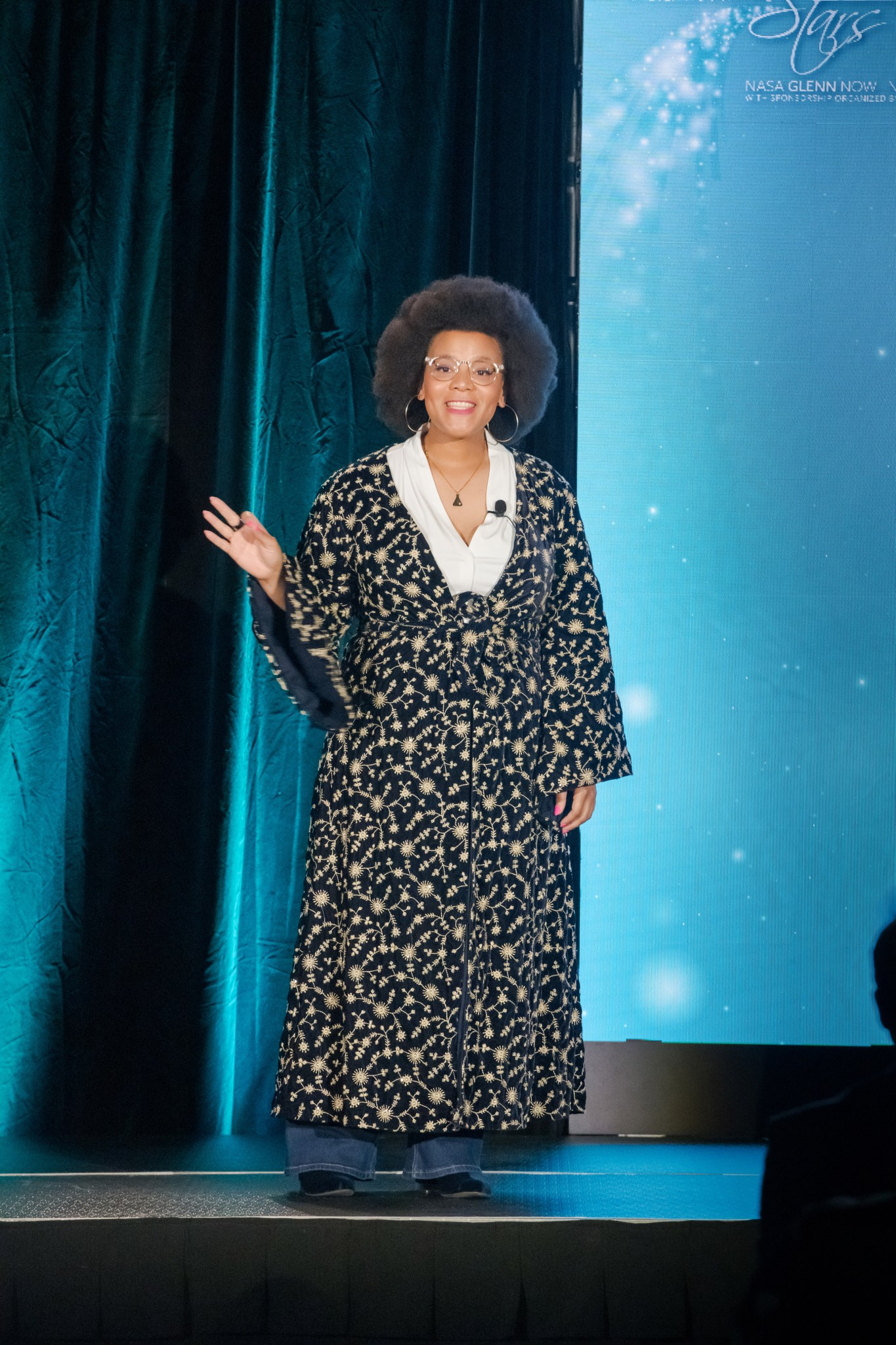 Dr. Jamesa Stokes smiles as she addresses an audience from a stage.