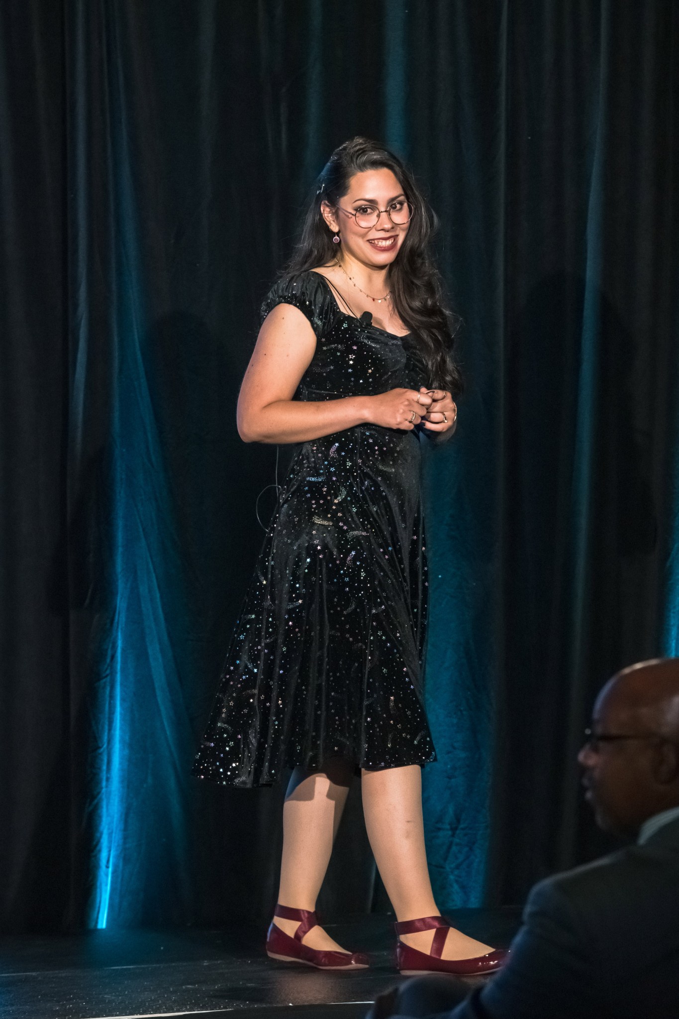 Gretchen Moralles-Valle smiles as she addresses an audience from a stage.