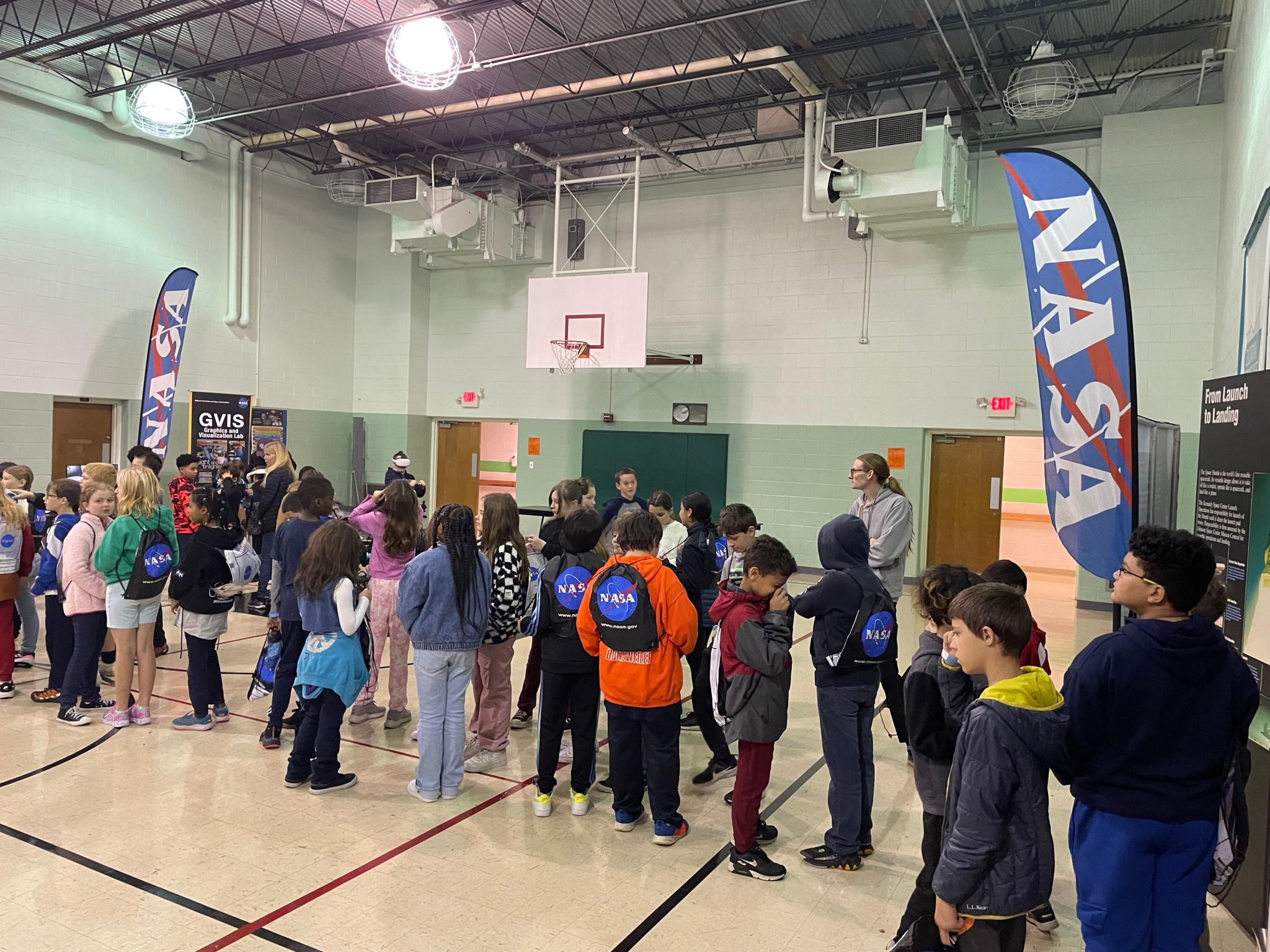 Young students stand in a line to participate in interactive exhibits.