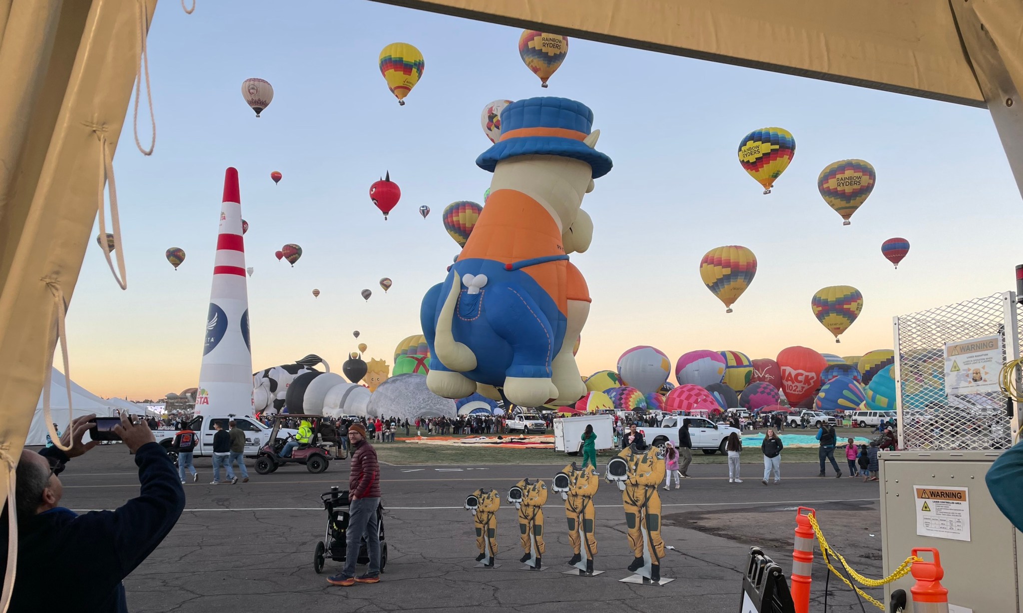 Colorful hot air balloons fill the sky as astronaut photo cutouts stand on the ground.