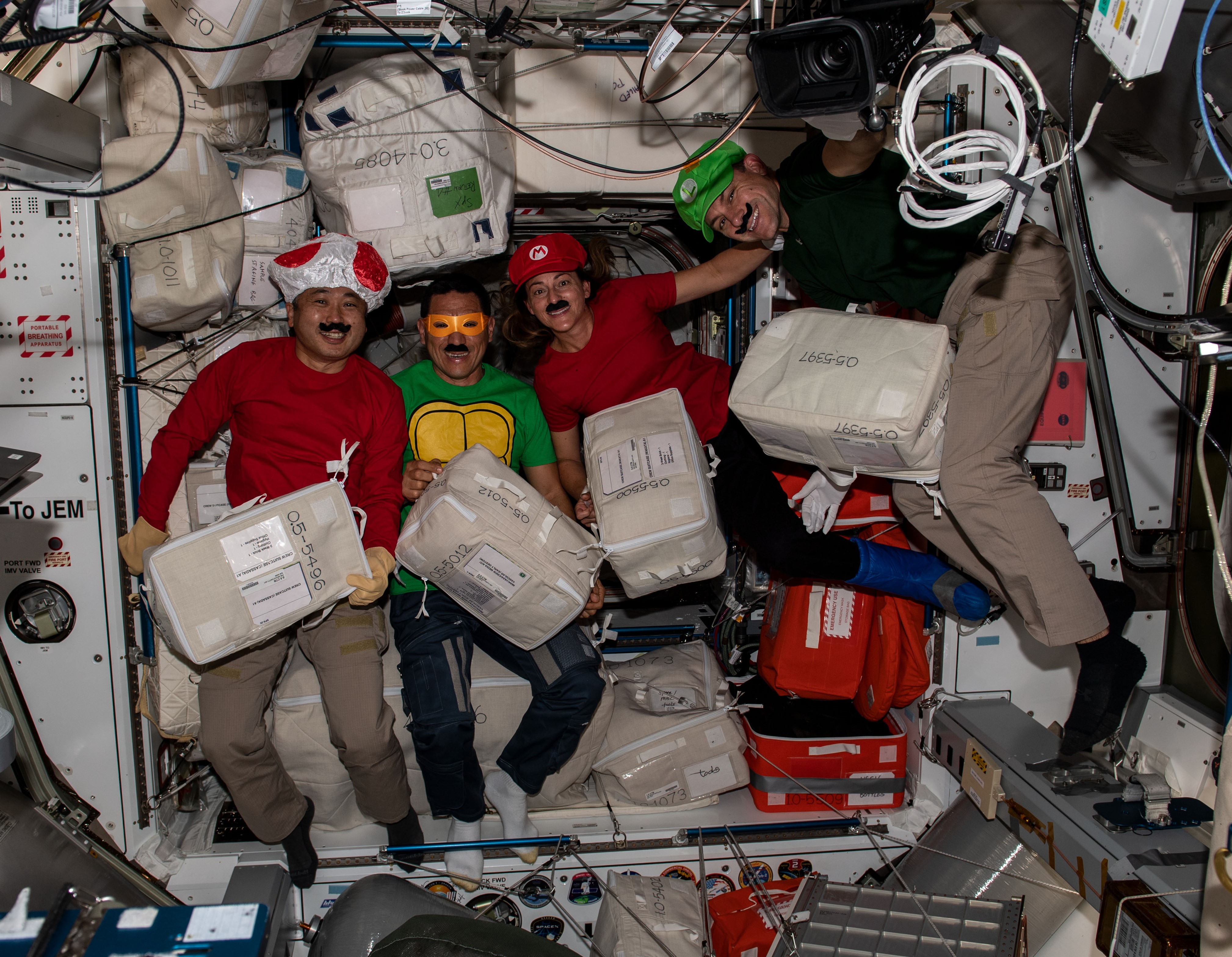 In 2022, Expedition 68 astronauts Koichi Wakata of the Japan Aerospace Exploration Agency, left, and NASA astronauts Francisco “Frank” C. Rubio, Nicole A. Mann, and Josh A. Cassada dressed as popular video game and cartoon characters, using stowage containers in their Halloween costumes and holding improvised trick-or-treat bags