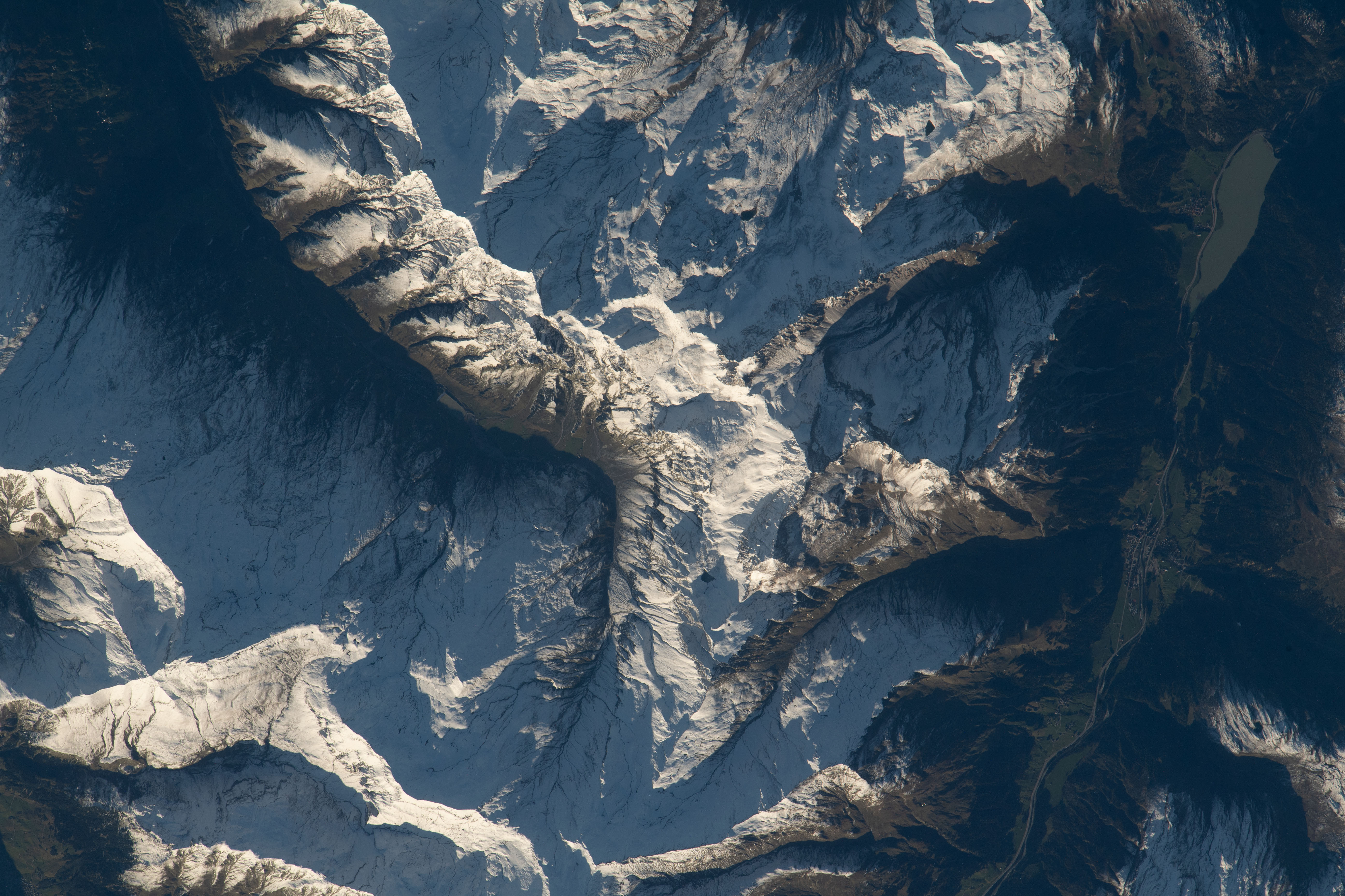 The sun reflects off peaks of the snow-capped Swiss Alps while casting shadows in the foothills of the mountain range as the International Space Station orbited 260 miles above Switzerland.