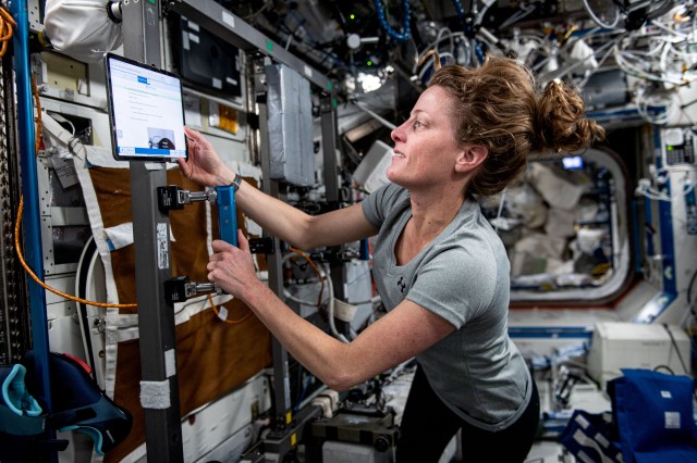 NASA astronaut and Expedition 70 Flight Engineer Loral O'Hara sets up an exercise cycle for a workout session inside the Destiny laboratory module aboard the International Space Station.