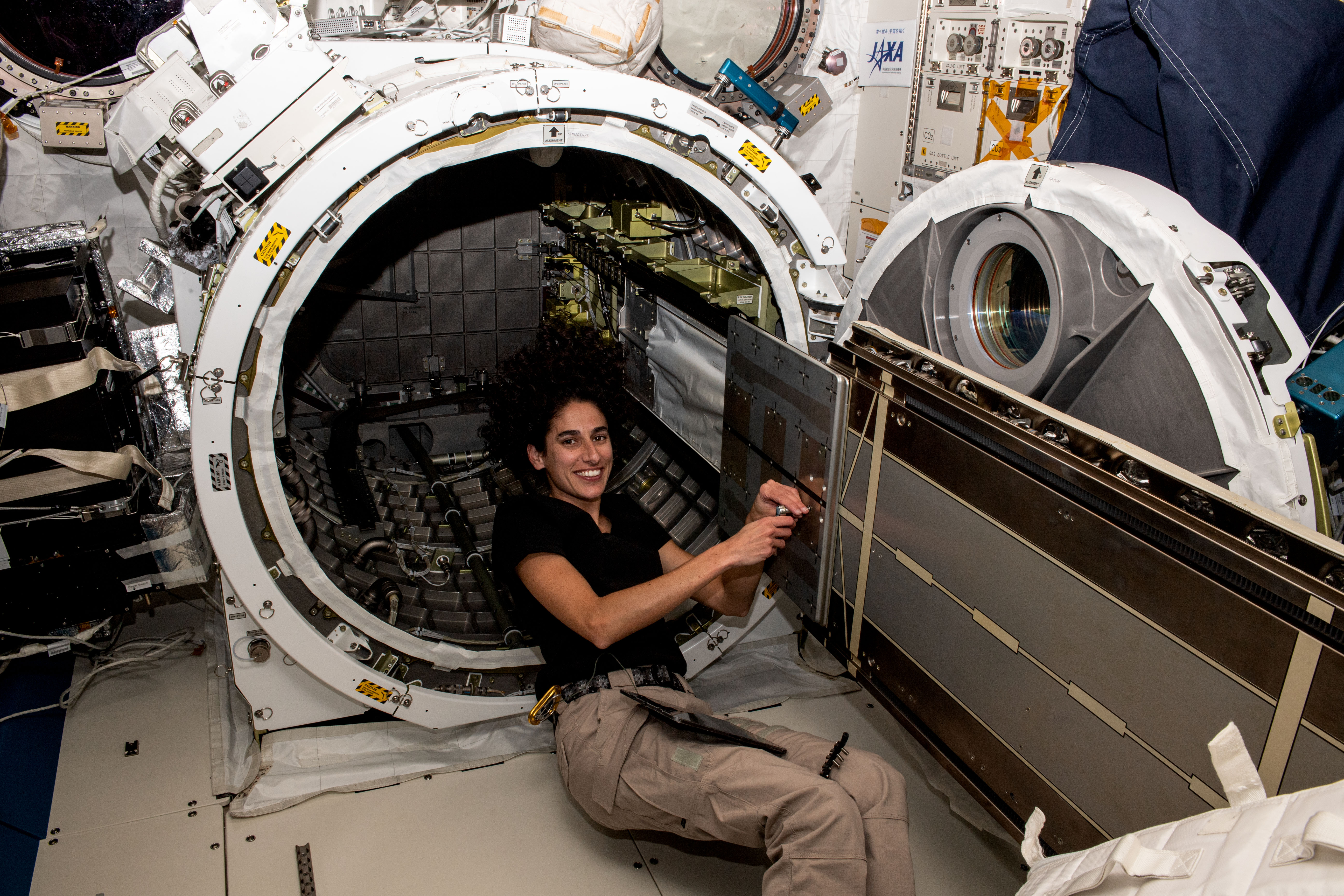 NASA astronaut and Expedition 70 Flight Engineer Jasmin Moghbeli prepares external hardware for retraction inside the Kibo laboratory module's airlock aboard the International Space Station.