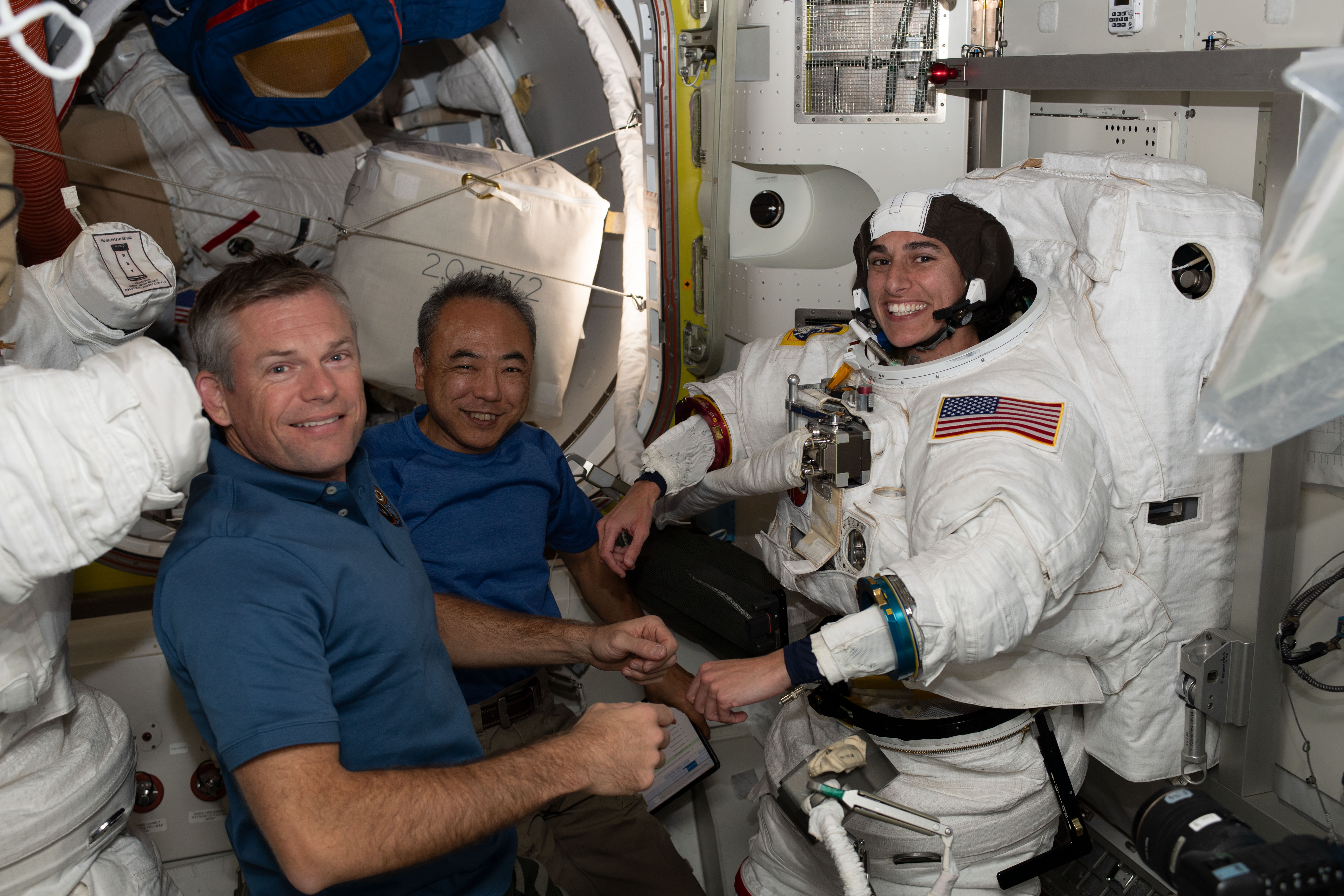 (From left) Astronauts Andreas Mogensen from ESA (European Space Agency) and Satoshi Furukawa from JAXA (Japan Aerospace Exploration Agency) assist NASA astronaut Jasmin Moghbeli as she tries on her spacesuit and tests its components aboard the International Space Station's Quest airlock in preparation for an upcoming spacewalk.