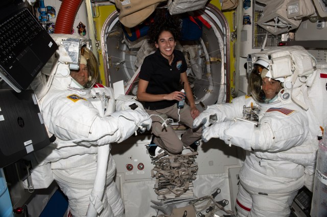 NASA astronaut Jasmin Moghbeli (center) assists astronauts Andreas Mogensen (left) from ESA (European Space Agency) and Loral O'Hara (right) from NASA as they try on their spacesuits and test the suits' components aboard the International Space Station's Quest airlock in preparation for an upcoming spacewalk.
