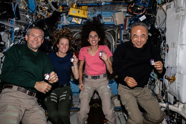(From left) Expedition 70 Commander Andreas Mogensen of ESA (European Space Agency); and Flight Engineers Loral O'Hara and Jasmin Moghbeli, both from NASA; and Satoshi Furukawa of JAXA (Japan Aerospace Exploration Agency), pose for a portrait aboard the International Space Station's Destiny laboratory module. The quartet is showing off crew active dosimeters that monitor the amount of radiation astronauts are exposed to in the microgravity environment.