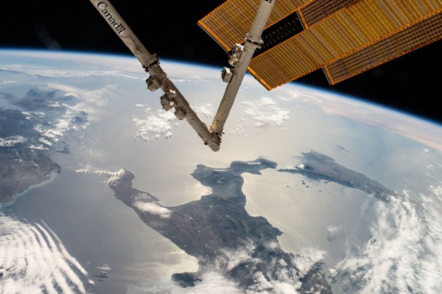 The boot of Italy and the island of Sicily are pictured from the International Space Station as it orbited 262 miles above. In the foreground, the Canadarm2 robotic arm and a pair of the main solar arrays extend from the orbiting laboratory.