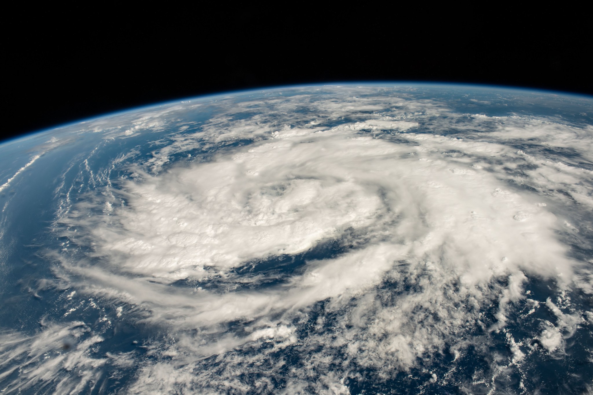 A storm, seen as massive, swirling white clouds dominates this image of Earth from the International Space Station. Peeking out from underneath the clouds and at the storm's edges is the deep blue of the Arabian Sea. In the background (top of image) is the curve of Earth, bordered by the darkness of space.