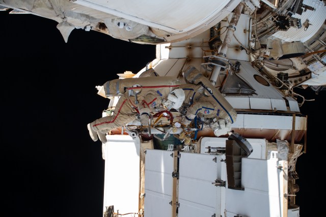 Expedition 70 Flight Engineers Oleg Kononenko (suit with red stripes) and Nikolai Chub (suit with blue stripes), both from Roscosmos, are pictured during a spacewalk to inspect a backup radiator, deploy a nanosatellite, and install communications hardware on the International Space Station's Nauka science module.