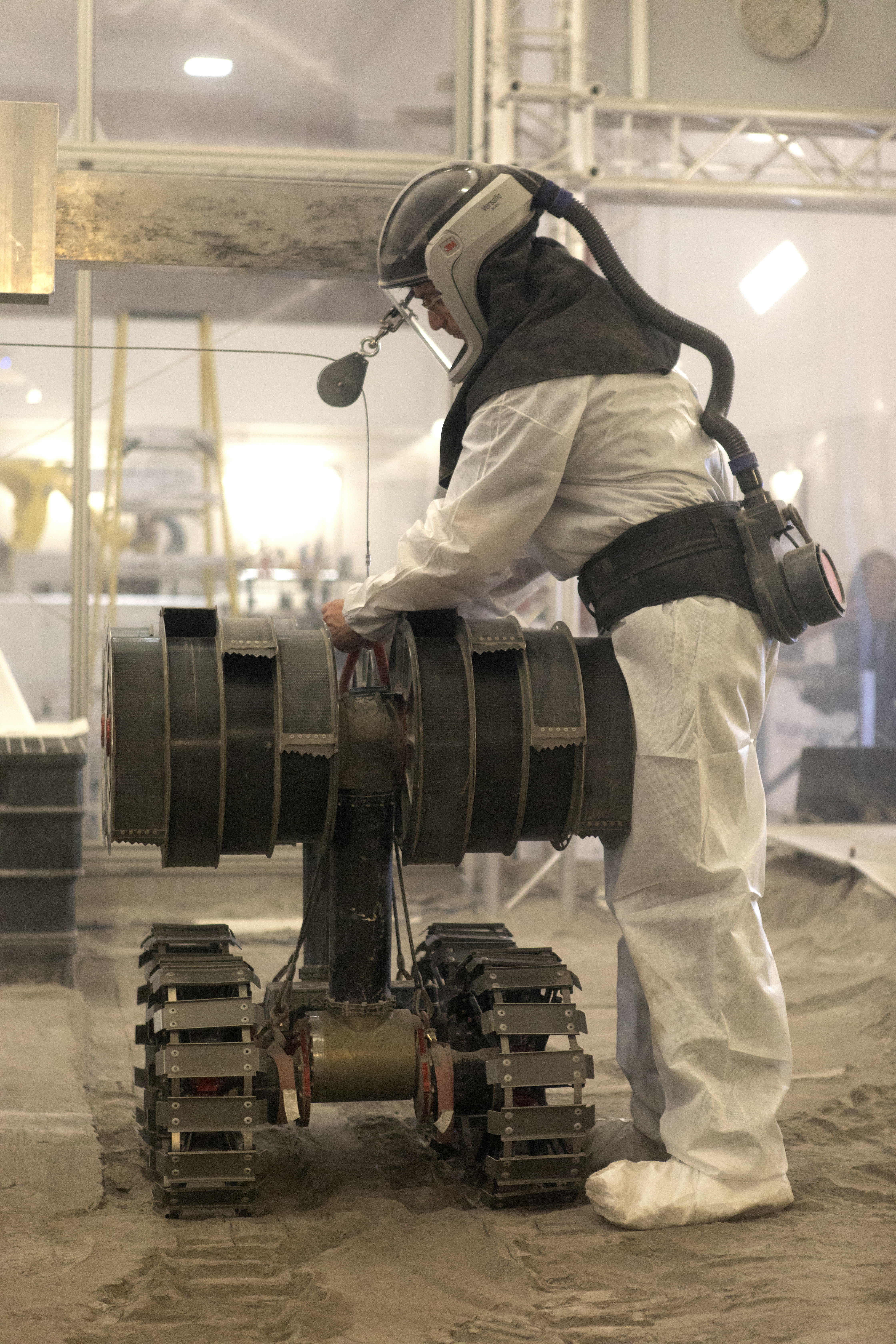 A robotics engineer makes adjustments to the Regolith Advanced Surface Systems Operations Robot (RASSOR) during testing in the regolith bin inside ...