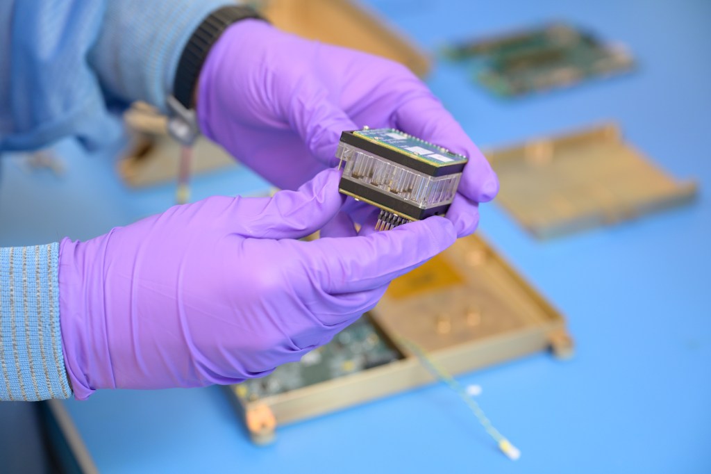 A person holds a small plastic cartridge with electronics on one side.