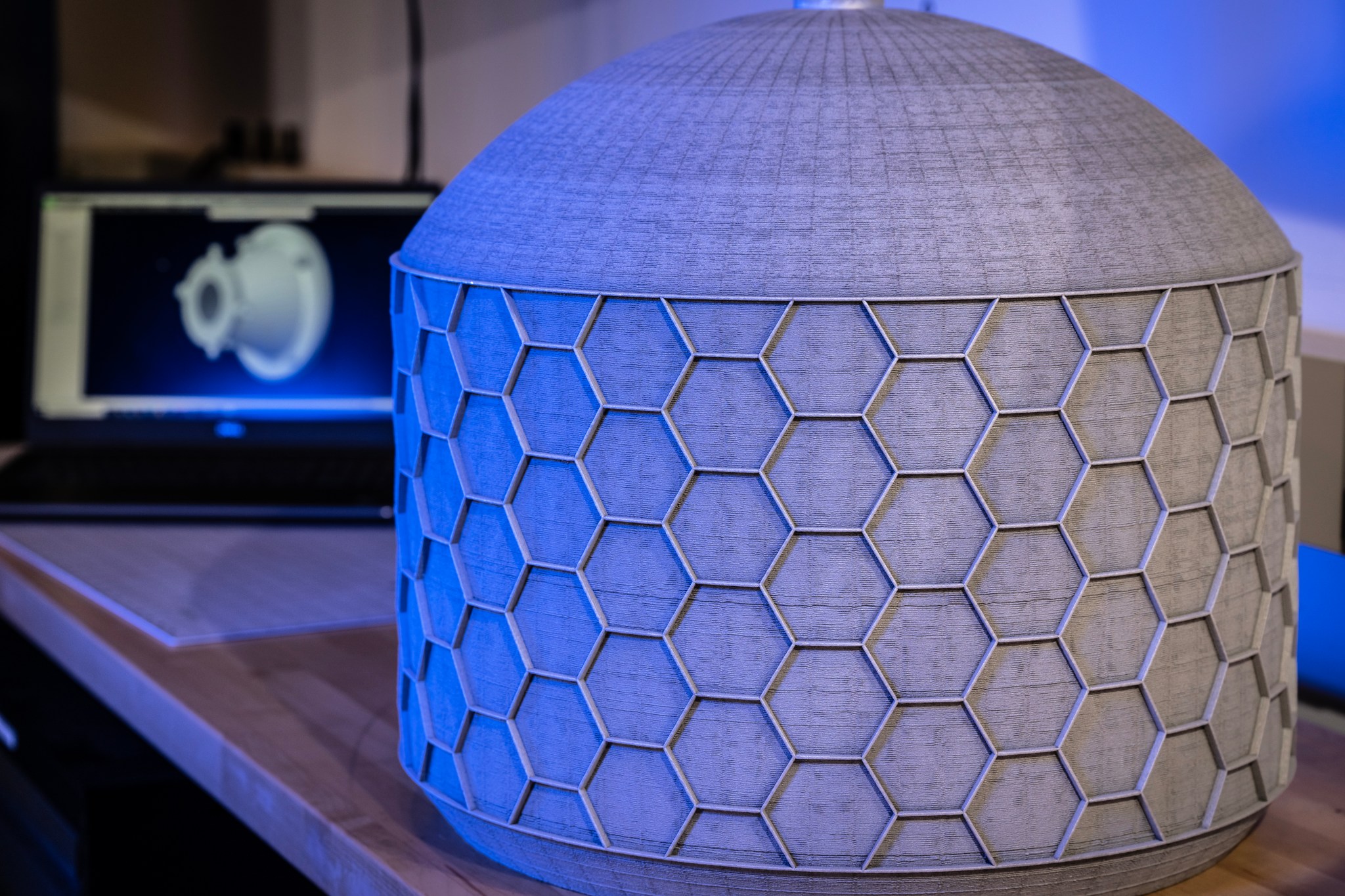A 3D printed circular demonstrator tank is shown on a table in a blue light