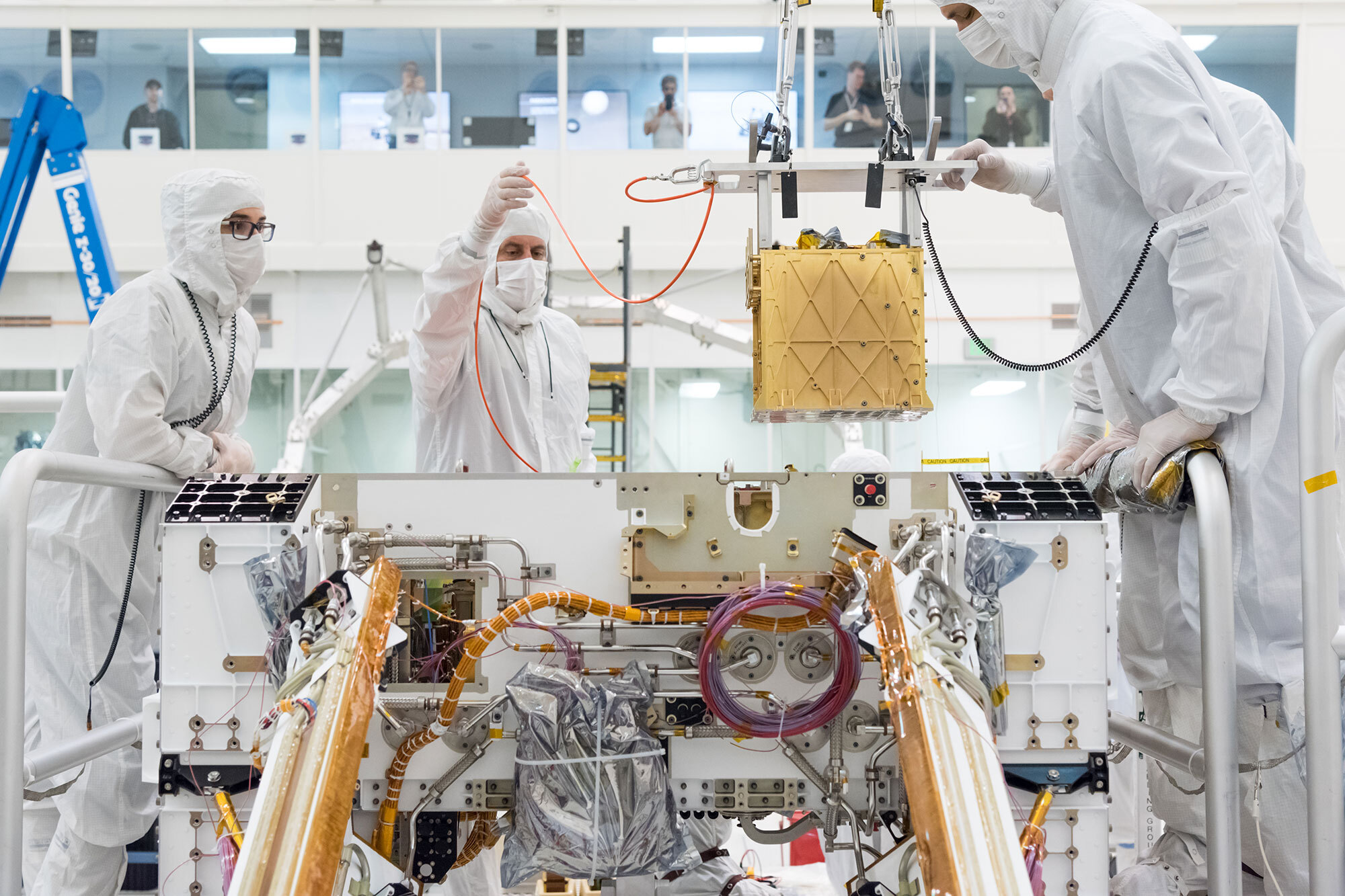 Technicians lower the Mars Oxygen In-Situ Resource Utilization Experiment (MOXIE) instrument into the belly of the Perseverance rover. Photo credit: NASA/JPL-CalTech