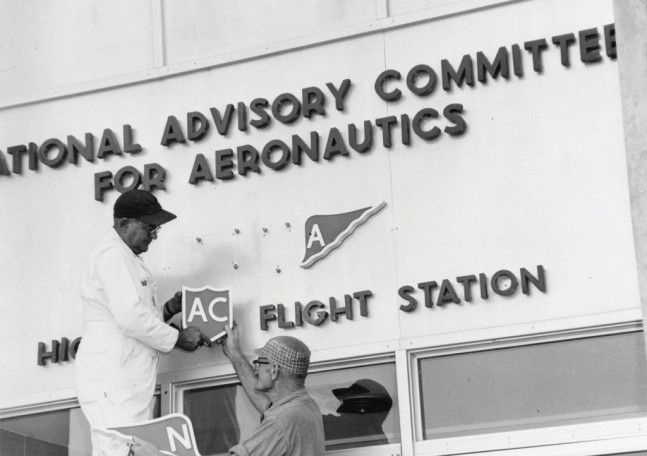 Workers removing the NACA logo at the High Speed Flight Station