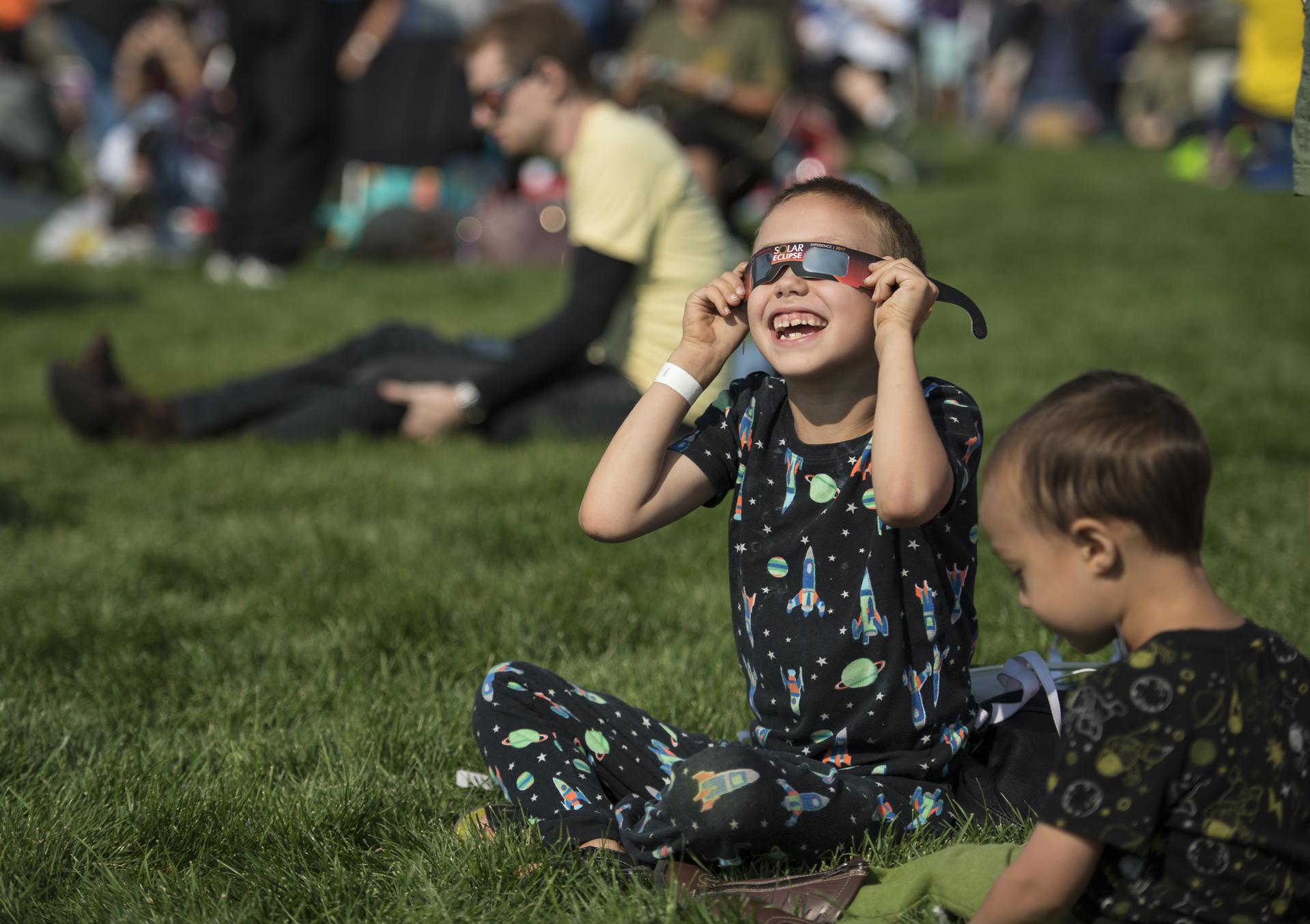 Un ragazzo guarda l'eclissi solare totale attraverso gli occhiali protettivi a Madras, Oregon, lunedì 21 agosto 2017. Un'eclissi solare totale ha attraversato una stretta porzione degli Stati Uniti contigui da Lincoln Beach, Oregon a Charleston, Carolina del Sud.  Un’eclissi solare parziale era visibile in tutto il continente nordamericano insieme a parti del Sud America, Africa ed Europa.  Foto